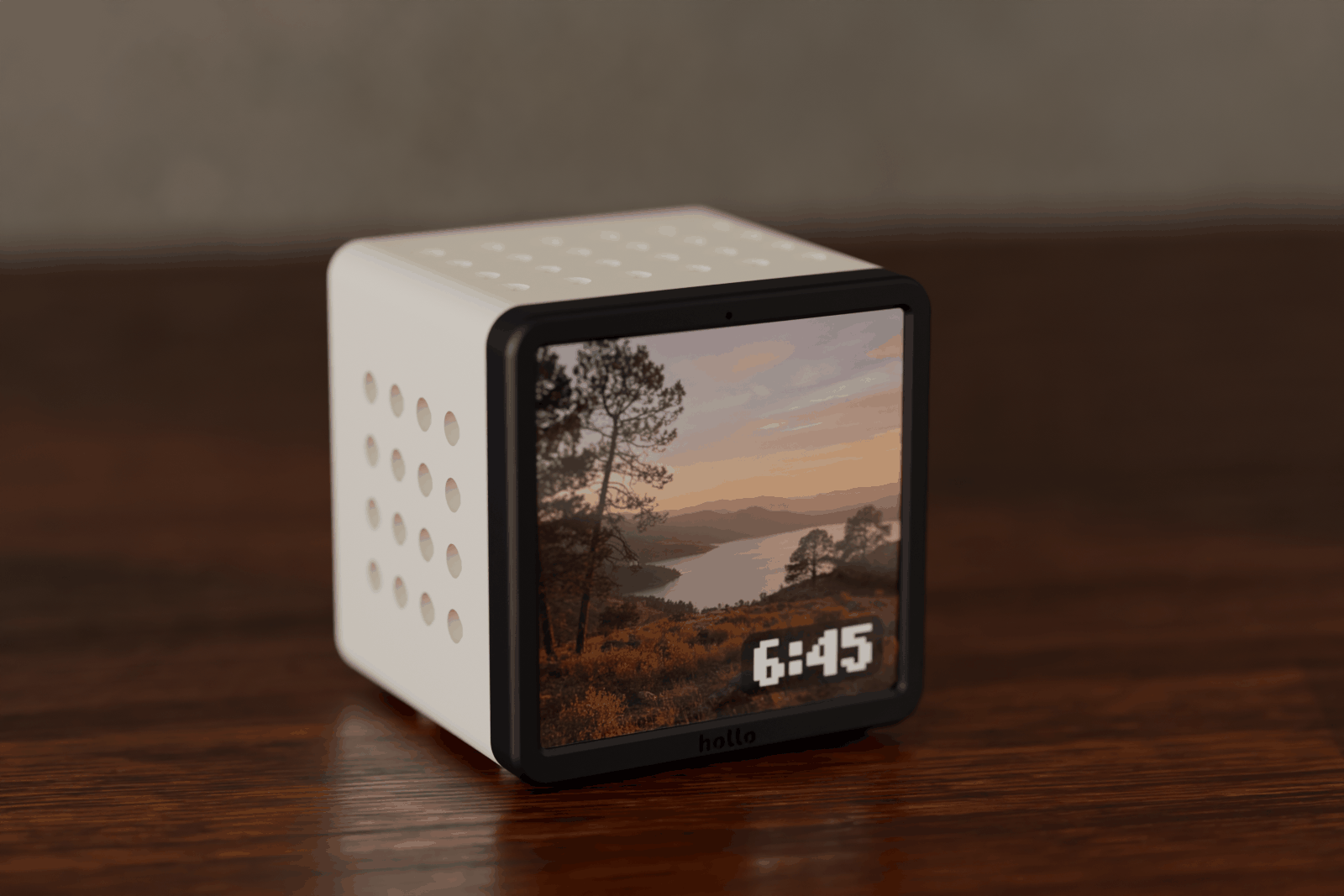 Rendered scene: a cream Hollo on a sunny desk showing a landscape photo of a lake at sunset, with the time in the corner of the screen